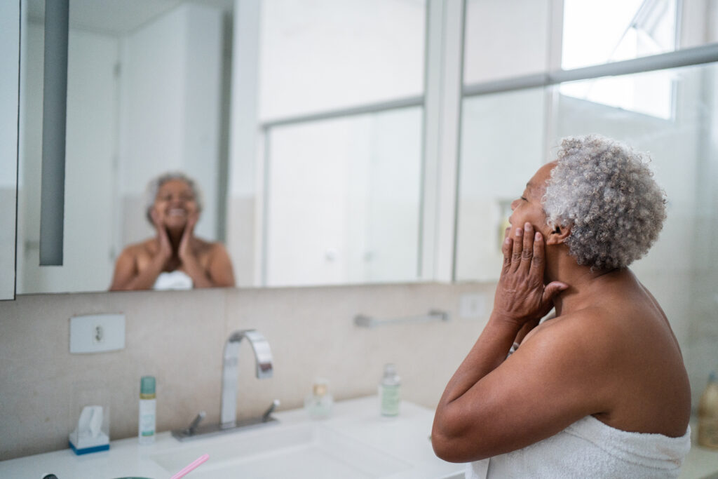  Senior woman applying body moisture in the bathroom at home